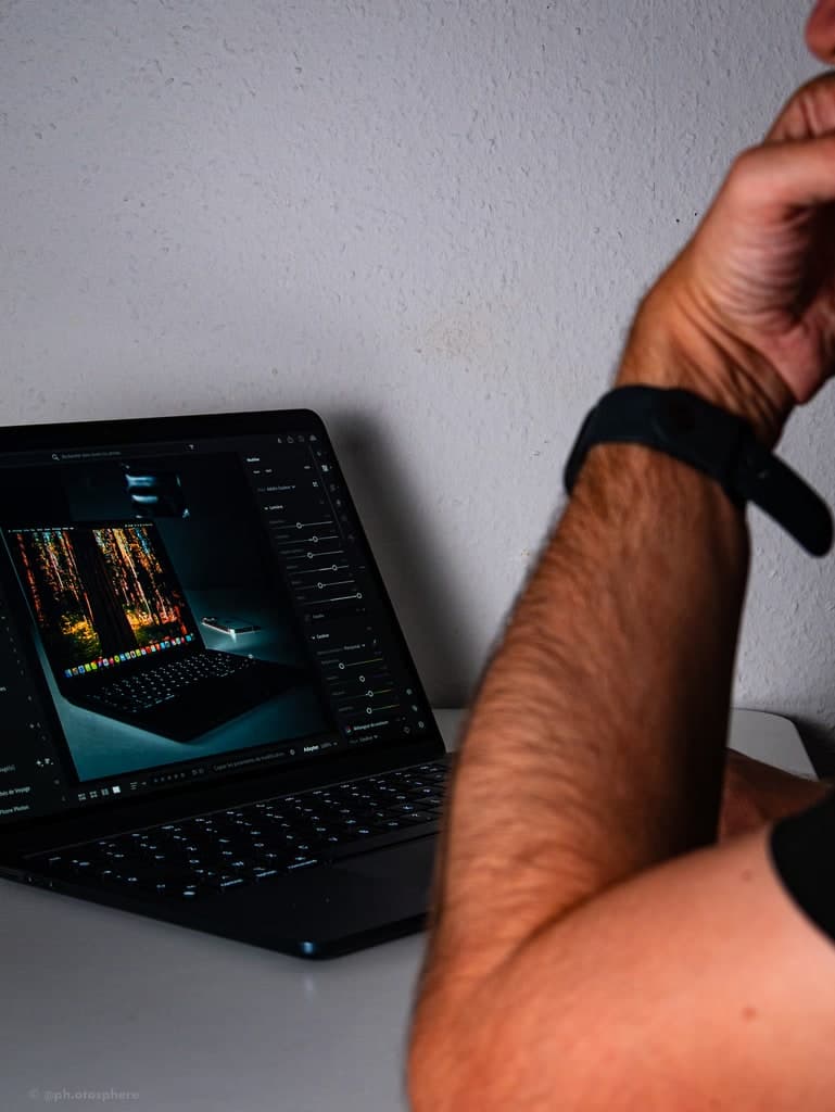 Avant-bras posé devant un ordinateur portable ouvert sur une séance de montage